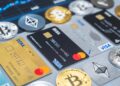 Tarjetas de crédito y débito sobre una mesa con distintas criptomonedas alrededor.