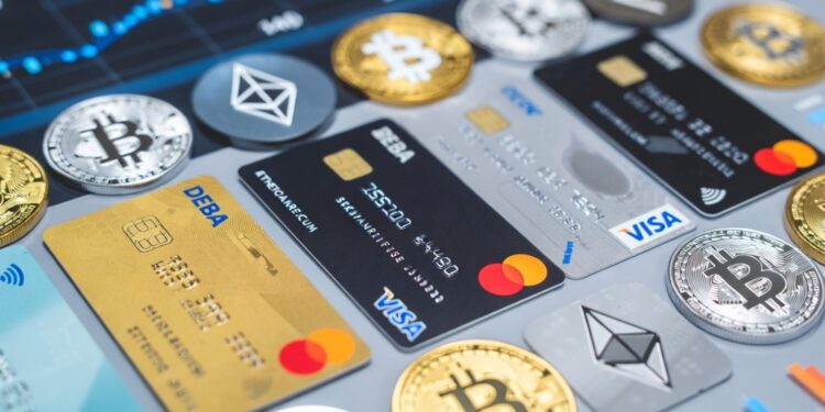 Tarjetas de crédito y débito sobre una mesa con distintas criptomonedas alrededor.