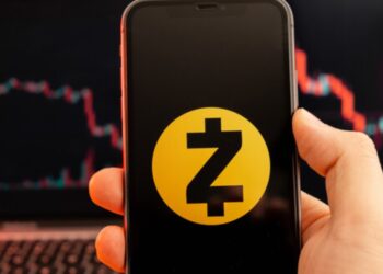 Mano sujetando un teléfono inteligente que refleja el logo de Zcash.