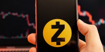 Mano sujetando un teléfono inteligente que refleja el logo de Zcash.