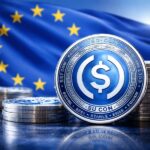 Monedas de la stablecoin USDC en primer plano con la bandera de la Unión Europea desenfocada al fondo.