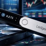 Dispositivo Ledger wallet frente a gráficos bursátiles y pantallas de trading financiero