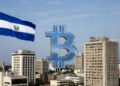 Logo de bitcoin con edificios de empresas y la bandera de El Salvador.