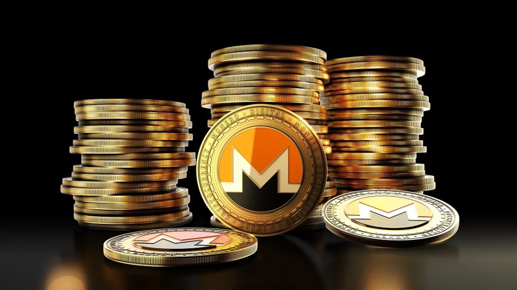 Una moneda física de monero delante de pilas de monedas