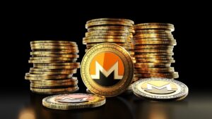 Una moneda física de monero delante de pilas de monedas