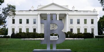 Logo de Bitcoin frente a la Casa Blanca, esta última tiene un letrero que dice "Closed (cerrado)".
