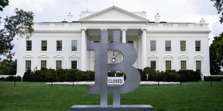 Logo de Bitcoin frente a la Casa Blanca, esta última tiene un letrero que dice "Closed (cerrado)".