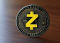 Moneda física de la criptomoneda Zcash sobre un escritorio de madera.