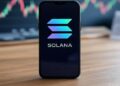 Smartphone sobre mesa de madera mostrando el logo de Solana en pantalla.