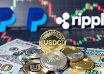 Monedas de USDC, y detrás billetes de dólares, las marcas PayPal y Ripple, y gráficos de mercados.