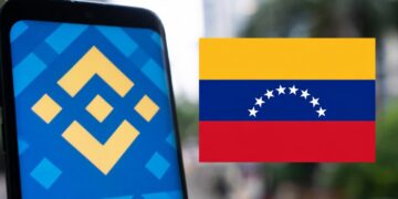 Teléfono inteligente que refleja el logo de Binance junto a una bandera de Venezuela.