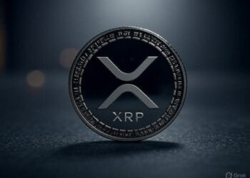 Una moneda física de XRP delante de un fondo gris.