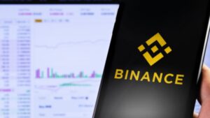 Mano sujetando un telรฉfono inteligente que muestra el logo de Binance.