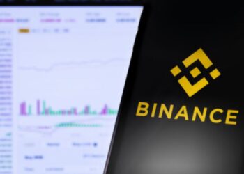 Mano sujetando un teléfono inteligente que muestra el logo de Binance.