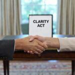 Par de manos estrechรกndose en una oficina de la Casa Blanca, con un documento que dice "Clarity Act" en el fondo.