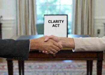 Par de manos estrechándose en una oficina de la Casa Blanca, con un documento que dice "Clarity Act" en el fondo.