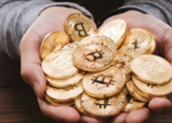 Dos manos sotienen un grupo de bitcoins físicos.