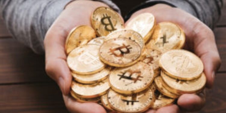 Dos manos sotienen un grupo de bitcoins físicos.