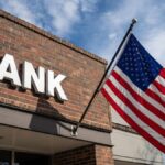 Edificio de ladrillos con un cartel que dice BANK, con la bandera de EE. UU. izada.