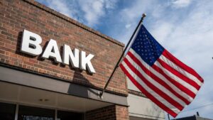 Edificio de ladrillos con un cartel que dice BANK, con la bandera de EE. UU. izada.