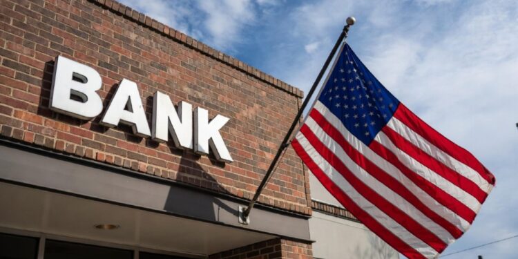 Edificio de ladrillos con un cartel que dice BANK, con la bandera de EE. UU. izada.