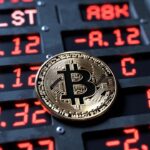 moneda de bitcoin y panel de acciones tecnolรณgicas en Wall Street con nรบmeros rojos
