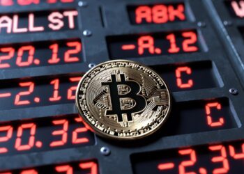 moneda de bitcoin y panel de acciones tecnológicas en Wall Street con números rojos