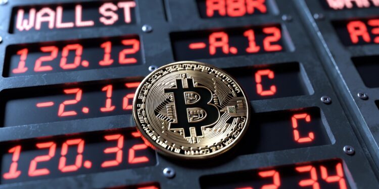 moneda de bitcoin y panel de acciones tecnológicas en Wall Street con números rojos