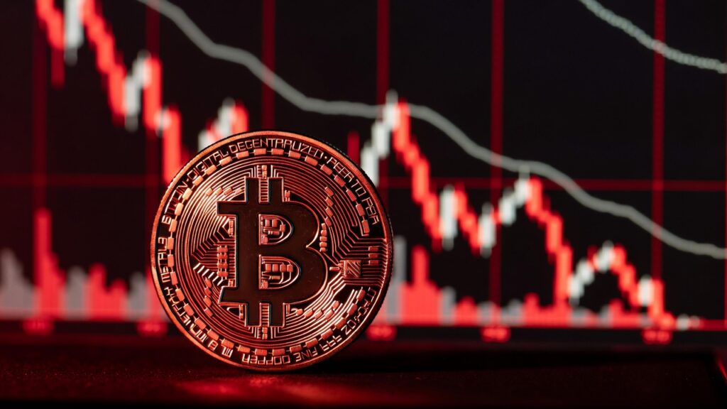 moneda de bitcoin y gráficos de precio en caída con luz roja