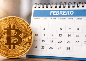 Una moneda física de bitcoin junto a un calendario de febrero.