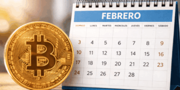Una moneda física de bitcoin junto a un calendario de febrero.