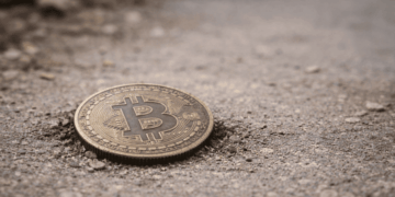 Una moneda física de bitcoin en el suelo.