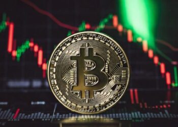 Moneda de bitcoin, gráfico de precio rojo en caída y luz verde iluminando.