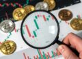 Lupa sobre gráfico de bitcoin y monedas BTC.