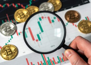 Lupa sobre gráfico de bitcoin y monedas BTC.