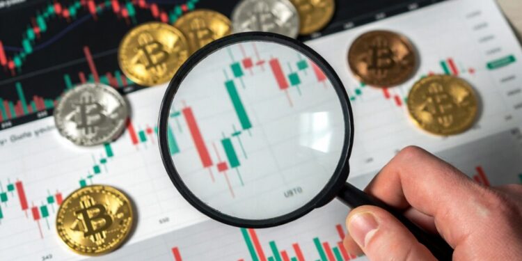Lupa sobre gráfico de bitcoin y monedas BTC.