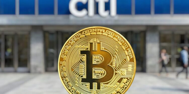 Una moneda física de Bitcoin dorada en primer plano con el logotipo de un banco Citi desenfocado al fondo