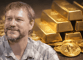 Fotografía de Nick Szabo en primer plano. En el fondo: lingotes de oro y monedas físicas de bitcoin.