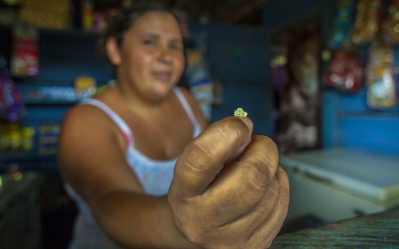 Mujer venezolana sosteniendo una pequeña pepita de oro en su mano dentro de una pequeña tienda.