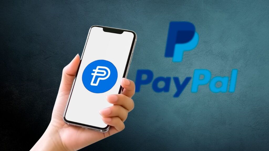 Smartphone mostrando el logo de PayPal PYUSD stablecoin con fondo azul.