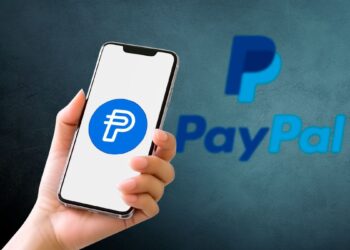Smartphone mostrando el logo de PayPal PYUSD stablecoin con fondo azul.