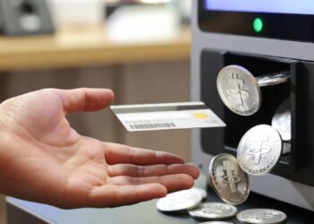 Una mano presentando una tarjeta sobre un cajero automático, del cual brotan monedas de USDT. Fuente: Imagen generada por Grok.