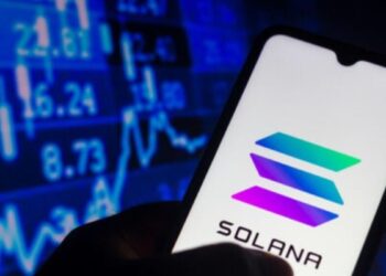 Smartphone con el logo de Solana en la pantalla y un fondo bursátil.