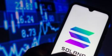 Smartphone con el logo de Solana en la pantalla y un fondo bursátil.