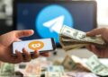 Manos intercambiando BTC con dinero alrededor y el logo de Telegram en el fondo.