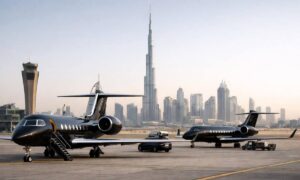 Tres jets privados de vuelos chárter estacionados en la pista con el horizonte urbano de Dubai al fondo.