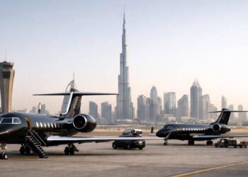Tres jets privados de vuelos chárter estacionados en la pista con el horizonte urbano de Dubai al fondo.
