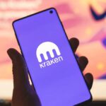 Persona sujetando un teléfono inteligente que muestra el logo de Kraken.