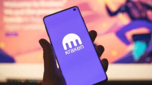 Persona sujetando un teléfono inteligente que muestra el logo de Kraken.