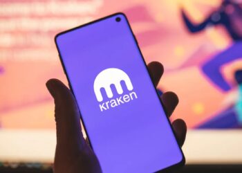 Persona sujetando un teléfono inteligente que muestra el logo de Kraken.